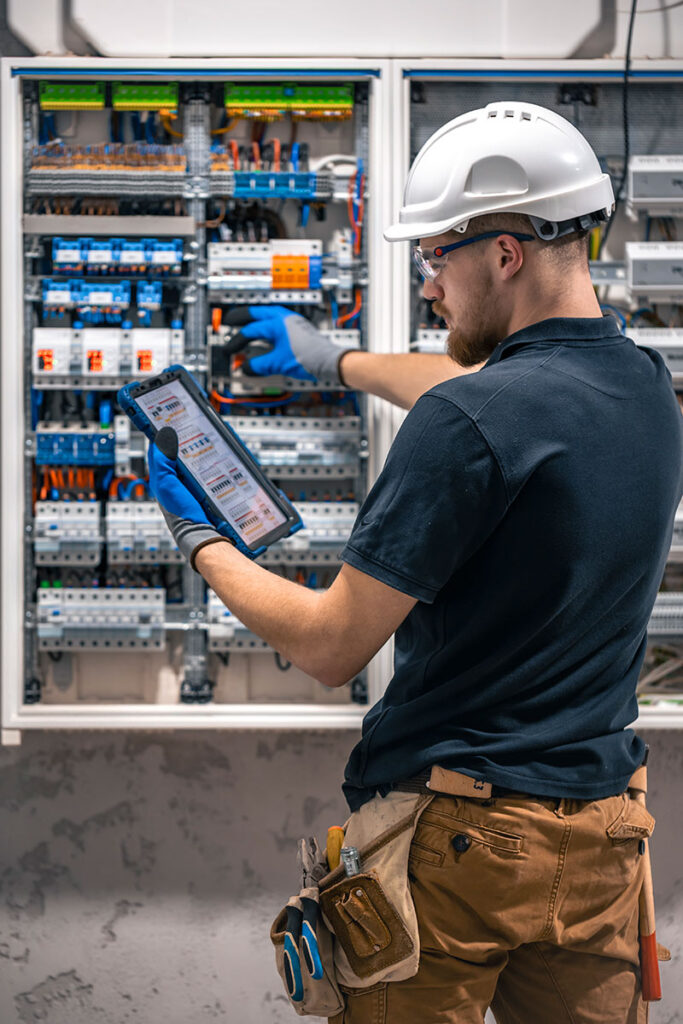 um-tecnico-eletrico-trabalhando-em-uma-central-com-fusiveis-usa-um-tablet